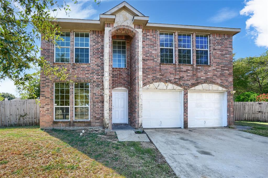 Two-story brick exterior featuring stone-accented arched entry, multi-pane windows, and a two-car garage