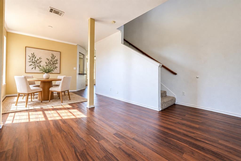 Wood-finish flooring throughout, staircase with a handrail, and structural pillar