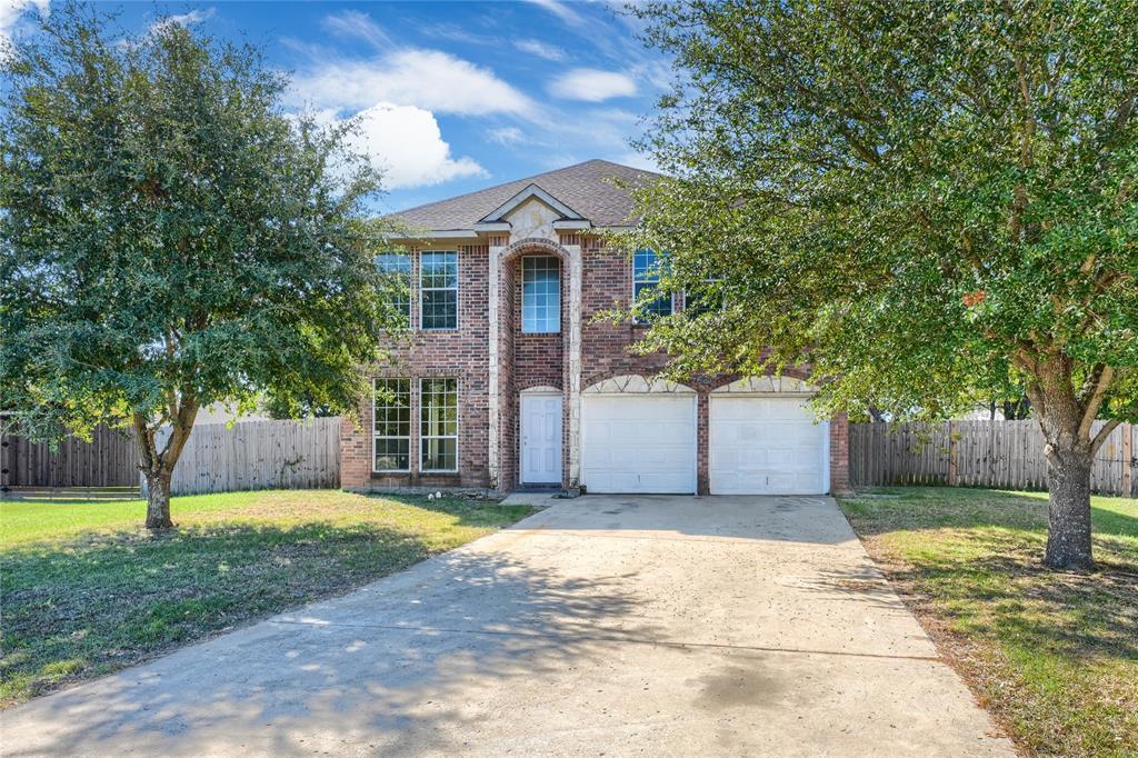 Two-story brick exterior featuring a multi-gabled roofline, an arched entryway, and an attached two-car garage