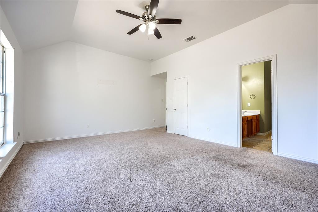 Vaulted ceiling featuring a central multi-blade ceiling fan, wall-to-wall carpeting, and a tall rectangular window