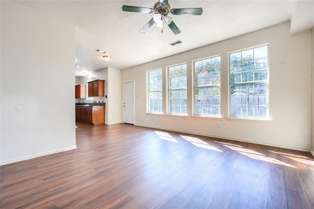 Open-concept room featuring wood-finish flooring, a ceiling fan with integrated lighting, and a row of large windows