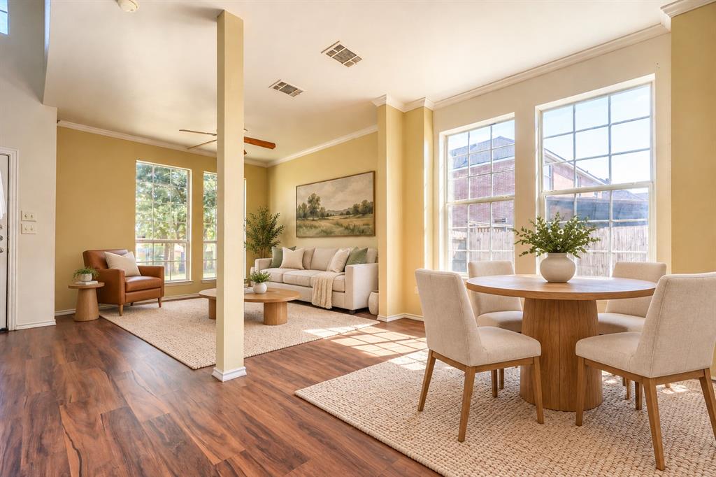 Open-concept floor plan featuring wood-finish flooring, multi-pane windows, and crown molding