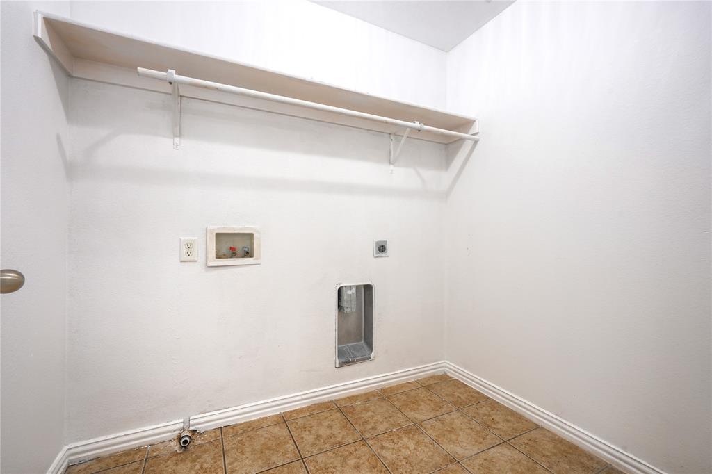 Utility area featuring ceramic tile flooring, a built-in overhead shelf, and an integrated hanging rod