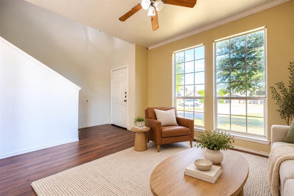 Living area featuring wood-finish flooring, two large paneled windows, high ceilings, and a ceiling fan