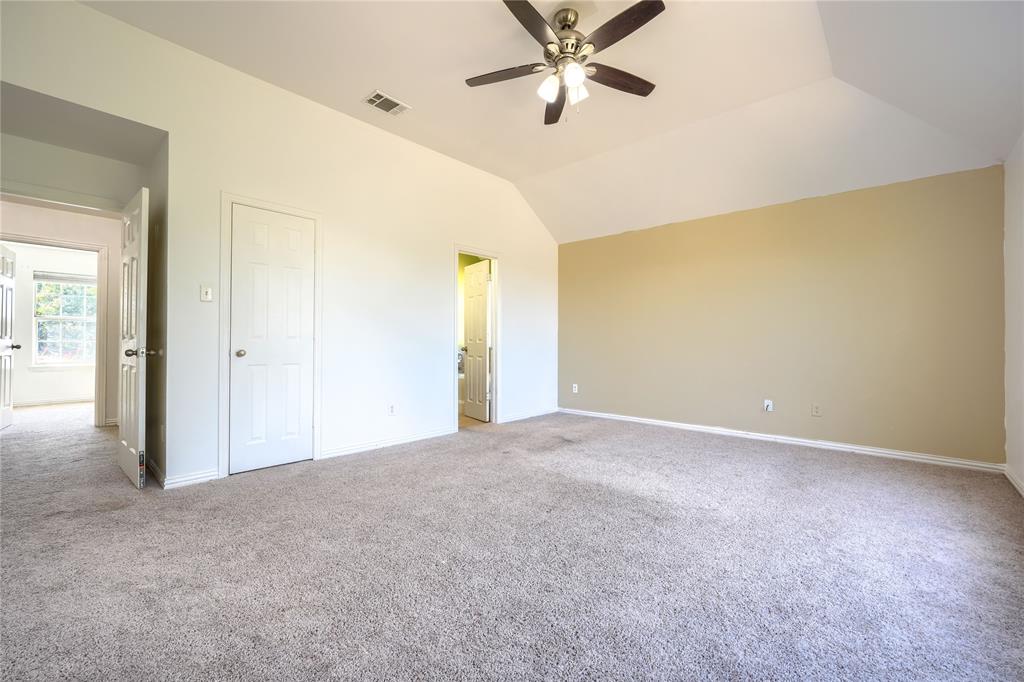Vaulted ceiling featuring a central multi-blade ceiling fan with integrated light kit, complemented by wall-to-wall carpeting and neutral interior wall finishes