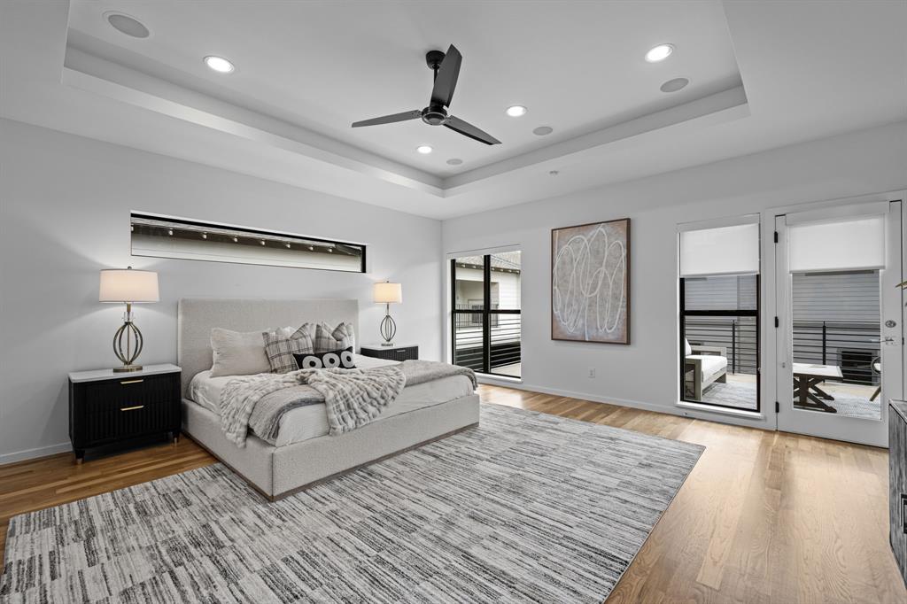Hardwood floors, a tray ceiling, and direct balcony access define the primary retreat.
