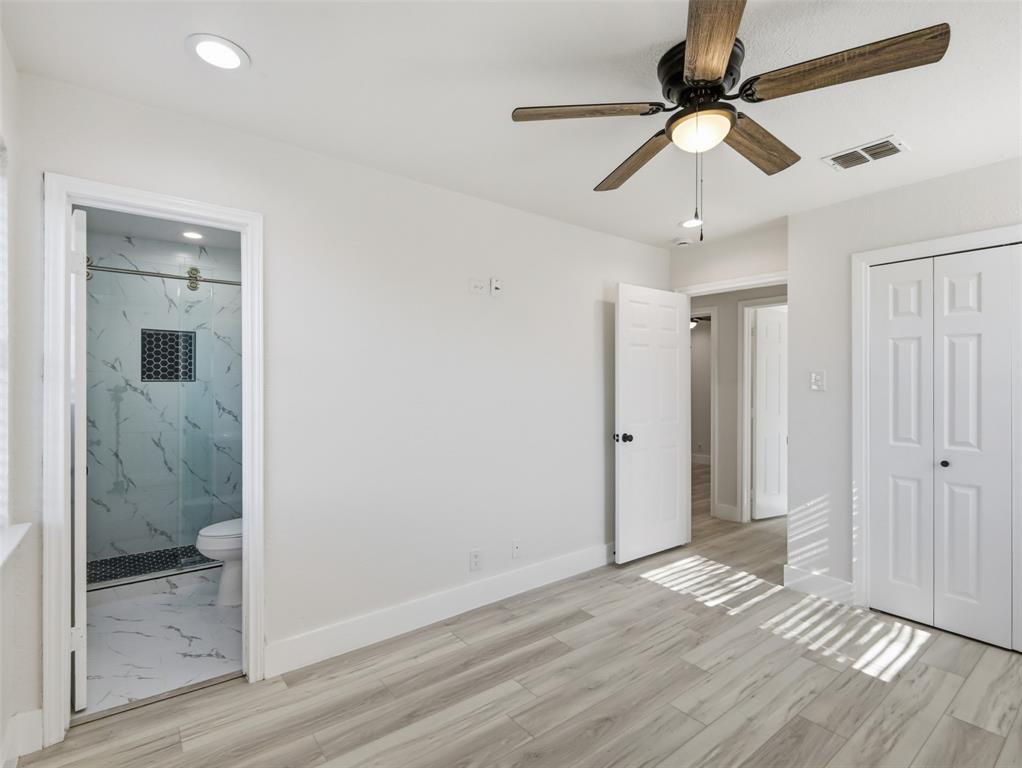 Room featuring wood-finish flooring, a ceiling fan with integrated lighting, recessed lighting, and a bathroom with a glass-enclosed shower and patterned tile inlay
