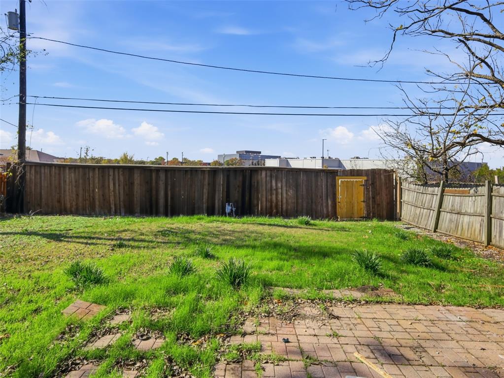 Backyard featuring a paved brick patio, lawn, and perimeter wood fencing with an integrated gate