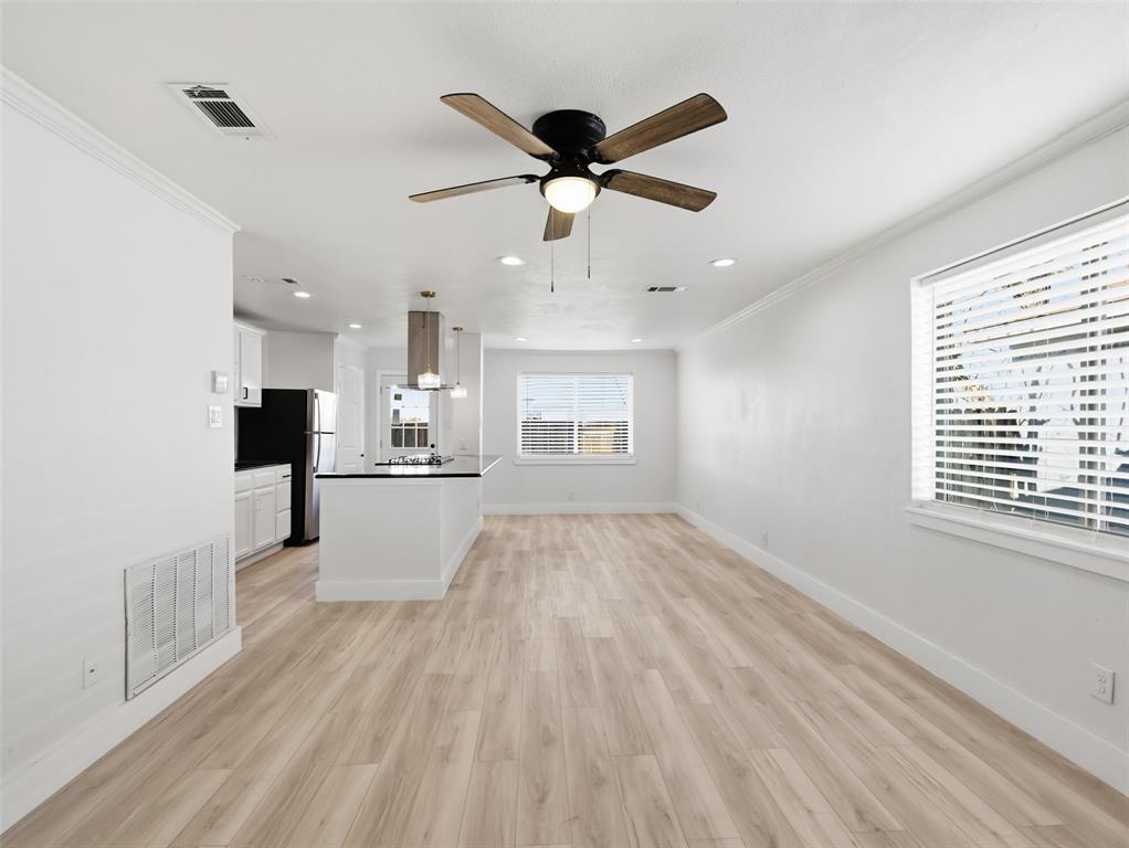 Open-concept interior featuring light wood-finish flooring, recessed lighting, a five-blade ceiling fan, and a kitchen island with a stone countertop Open-concept interior featuring light wood-finish flooring, recessed lighting, a five-blade ceiling fan, and a kitchen island with a stone countertop