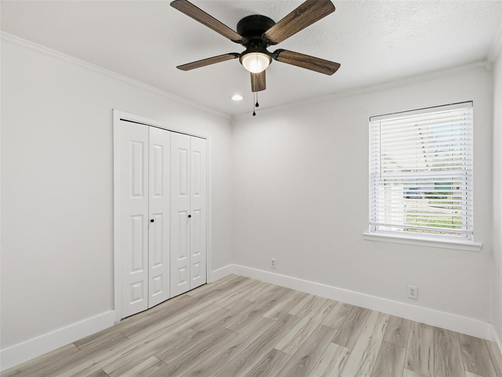 Room featuring wood-finish flooring, a ceiling fan with integrated lighting, bifold closet doors, and a window with horizontal blinds