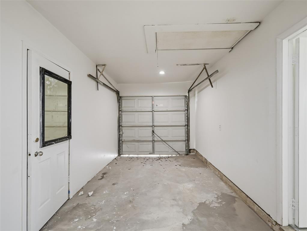 Enclosed garage space featuring a paneled metal overhead door, concrete flooring, and a side access door with a window insert