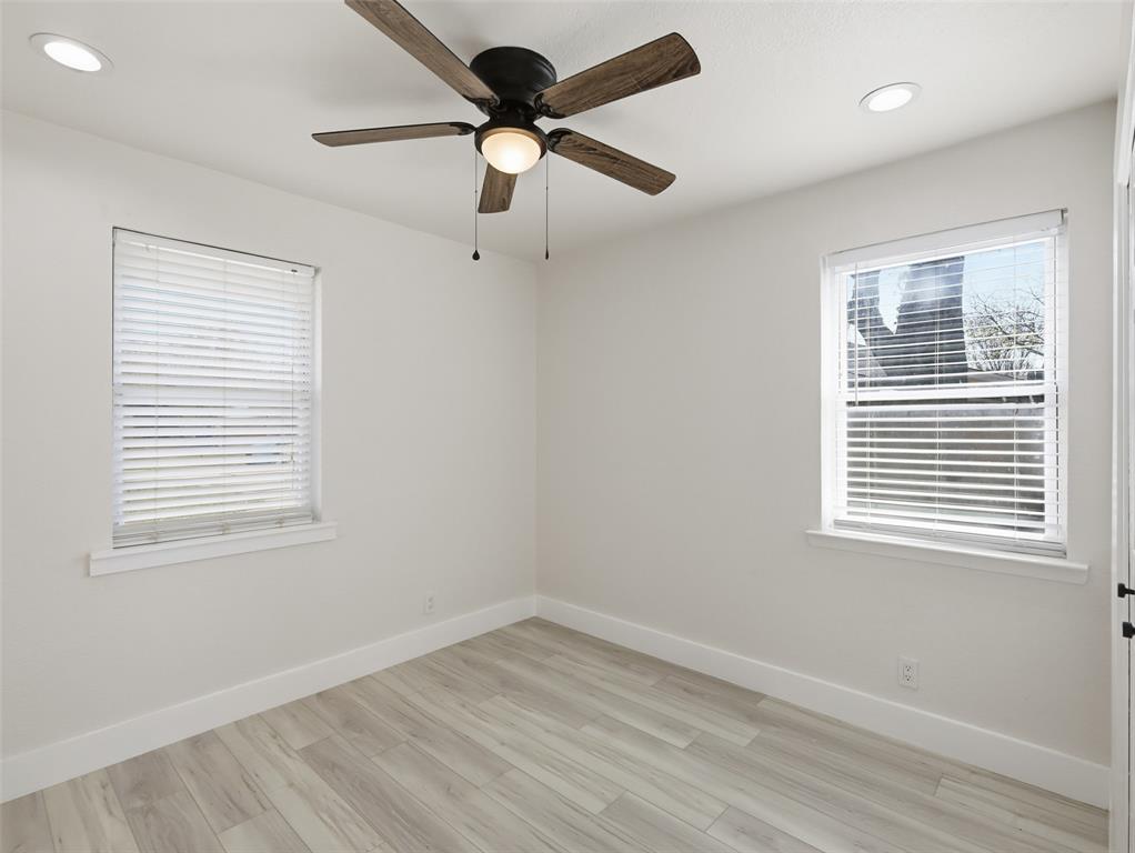 Room featuring wood-finish flooring, recessed lighting, a ceiling fan with integrated light, and two windows with blinds