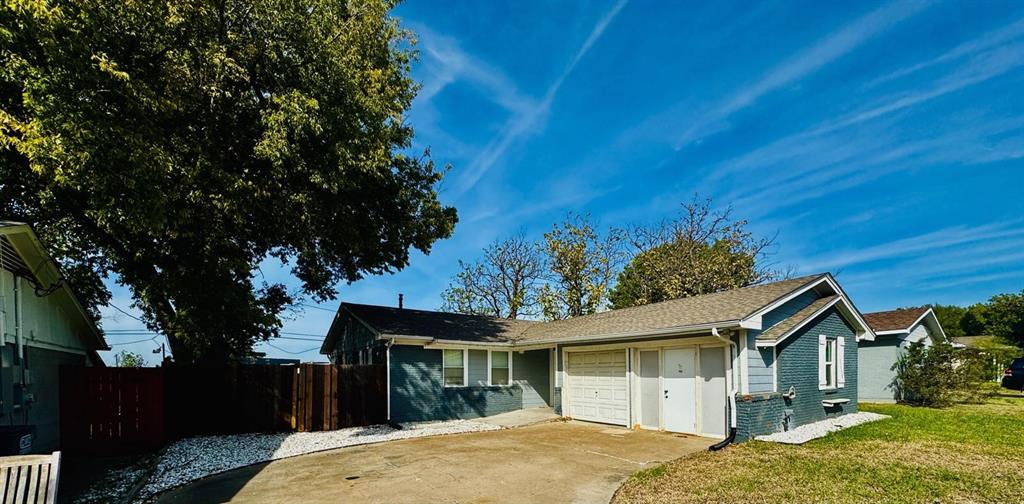 Single-story residence featuring a painted brick exterior, attached garage, concrete driveway, and wooden privacy fencing Single-story residence featuring a painted brick exterior, attached garage, concrete driveway, and wooden privacy fencing