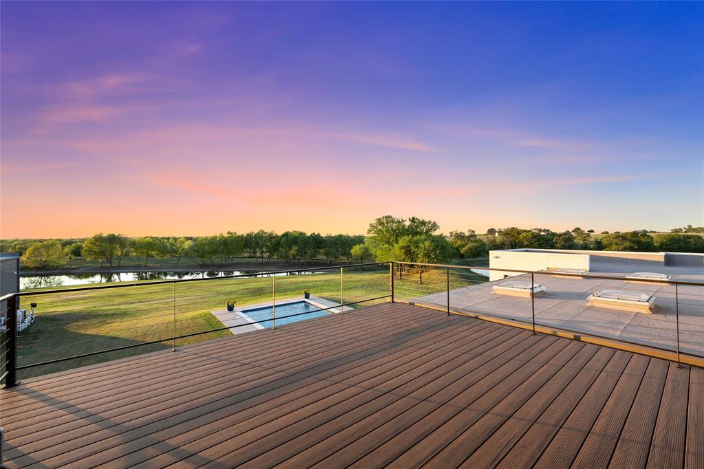 Elevated deck featuring composite wood-finish decking and a cable railing system, overlooking a private swimming pool, pond, and expansive acreage