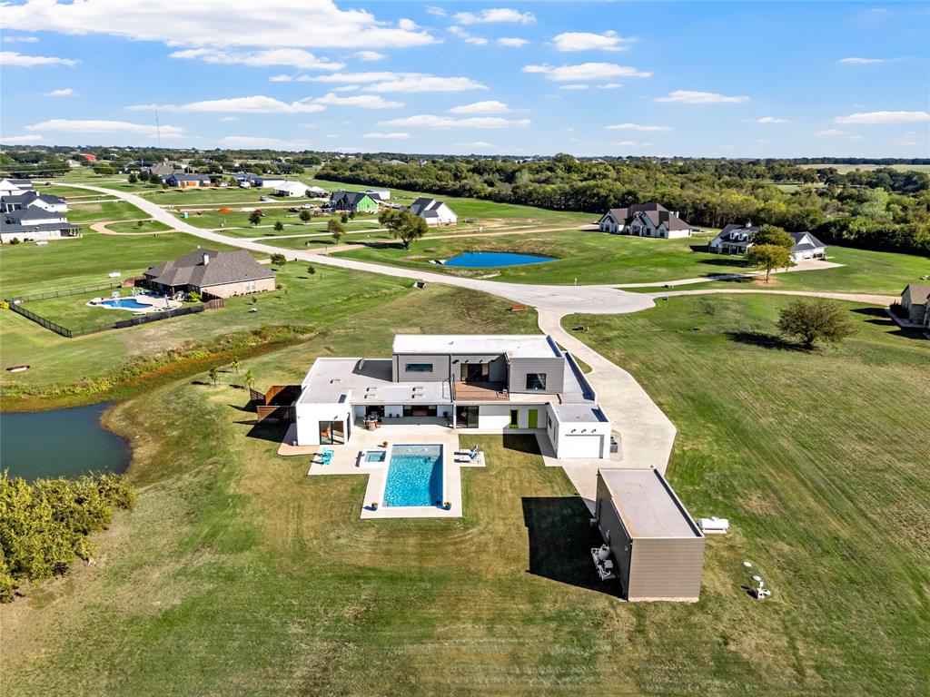 Contemporary multi-level exterior featuring flat roof lines, a rectangular swimming pool with integrated spa, concrete hardscaping, and a detached RV/Boat garage in addition to 3 car attached garage and 1 car workshop garage.