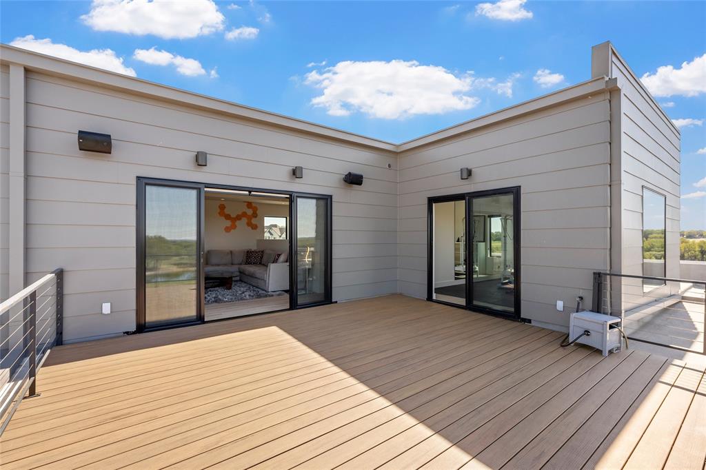 Rooftop terrace featuring horizontal siding, composite decking, metal cable railings, and dual sliding glass door entryways to Den and Exercise room.