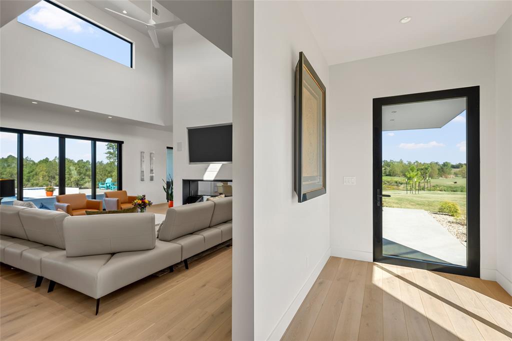 Open-concept interior featuring double-height ceilings, wood flooring, recessed lighting, and a modern kitchen with integrated cabinetry.