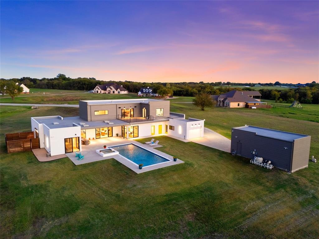 Contemporary multi-level exterior featuring stucco and siding, a rectangular swimming pool with an integrated spa, a second-story balcony, and a detached RV/Tractor garage with parallel shop.