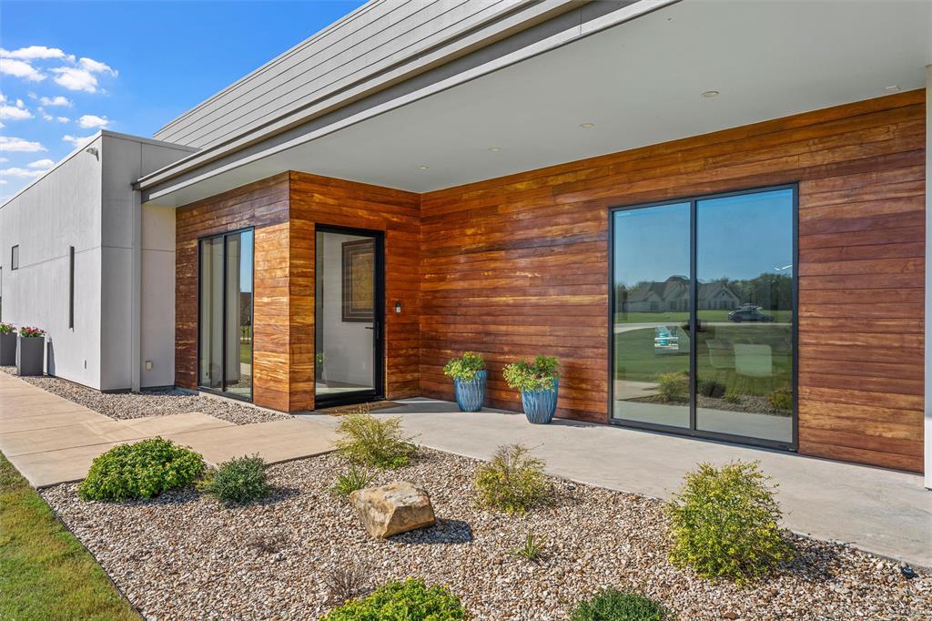 Contemporary exterior featuring horizontal wood-plank siding, smooth stucco finish, large glass sliding doors, recessed lighting, and a concrete walkway