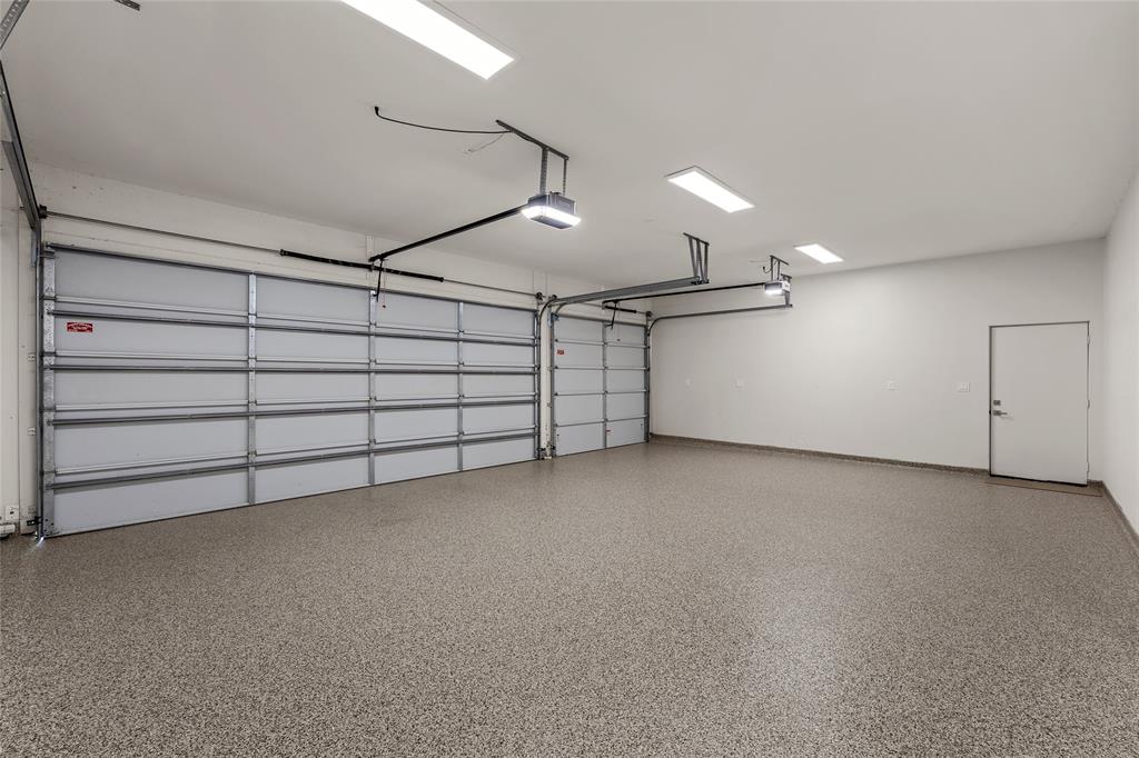 Solar ready Three-car attached garage featuring epoxy-coated flooring, dual overhead app and wifi enabled door systems, EV ready, high-output flush-mount lighting, and a separate pedestrian entry door and a large climate controlled storage area