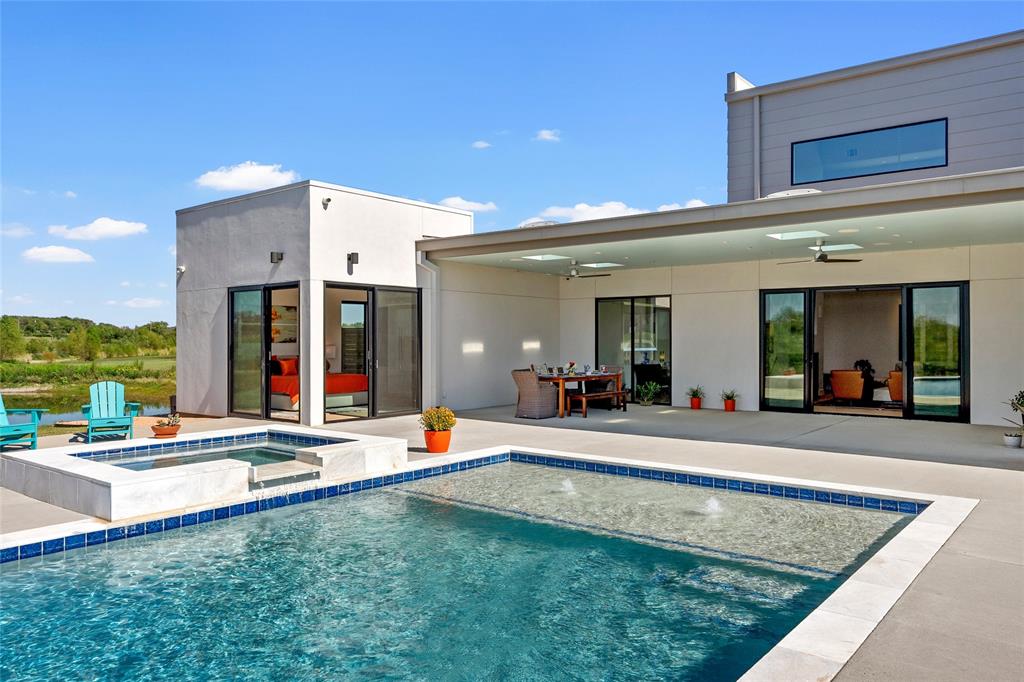 Modern exterior featuring a covered concrete patio, integrated pool and spa with tile detailing, and floor-to-ceiling glass sliding doors