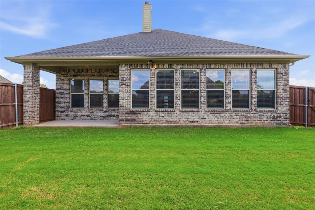 Brick exterior featuring a covered patio, hipped roofline, and multiple grid-pattern windows