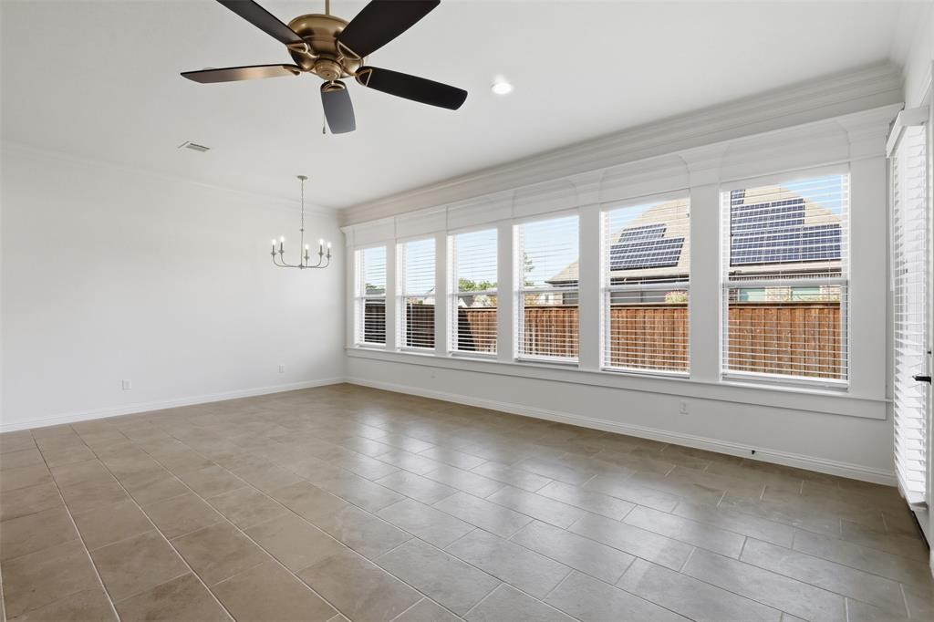 Large interior space featuring neutral tile flooring, expansive multi-pane windows with trim detailing, a tiered chandelier, and a ceiling fan with integrated lighting