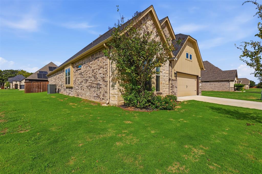 Exterior featuring a multi-textured facade of brick and vertical siding, a pitched roofline, and an attached garage with a concrete driveway