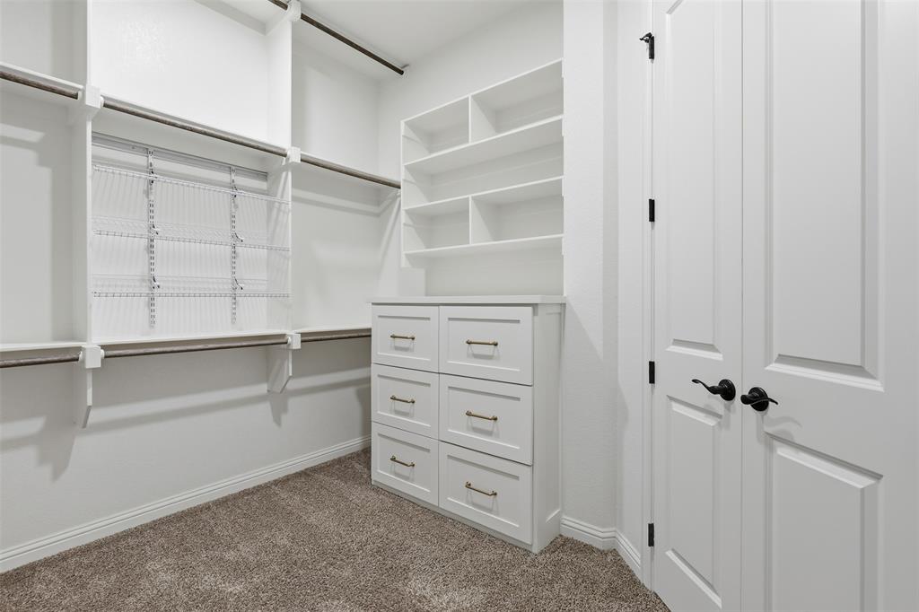 Custom storage space featuring white built-in shelving, integrated dresser drawers with metallic hardware, and adjustable wire racks