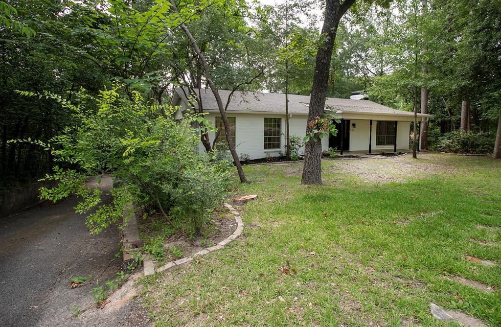 Single-story home exterior featuring a white painted brick facade, covered front porch with support pillars, and asphalt driveway