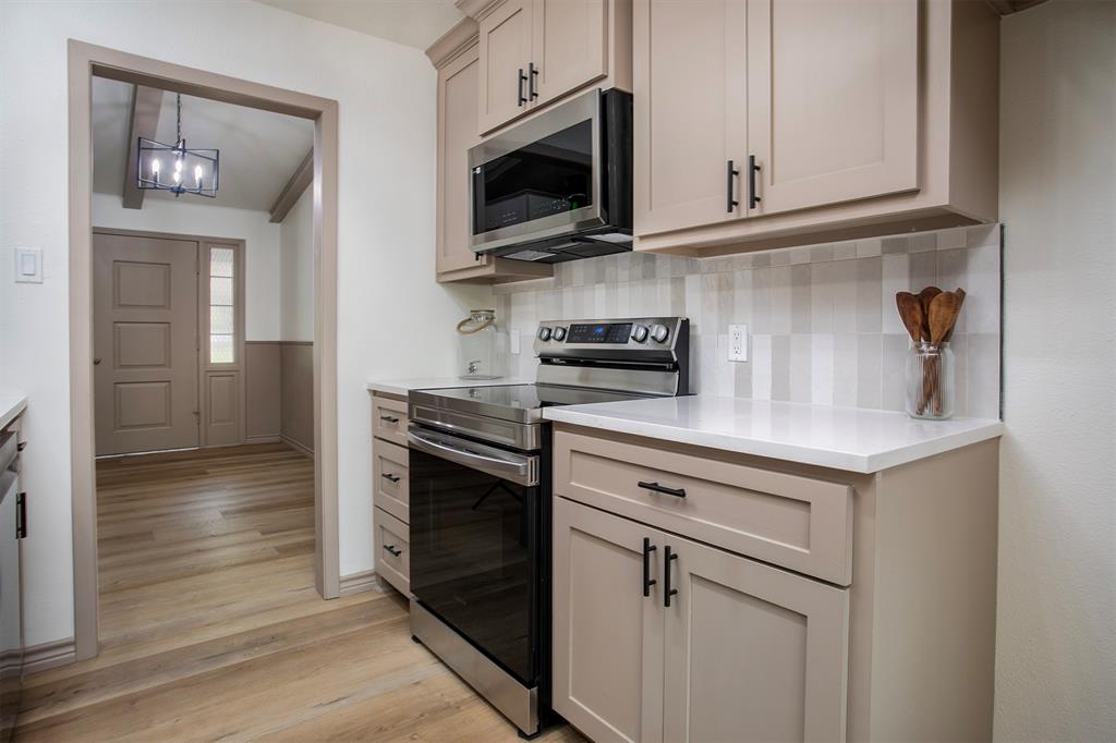 Kitchen featuring shaker-style cabinetry, quartz countertops, a tiled backsplash, and stainless steel appliances