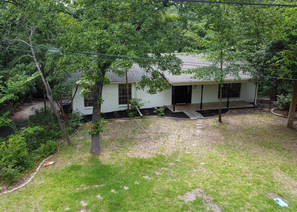 Painted brick exterior featuring a covered front porch, multi-pane windows, and a mature tree-lined lot