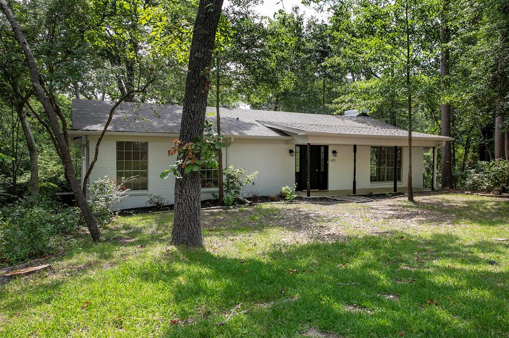 Painted brick exterior featuring a covered front porch, multi-pane windows, and a mature tree-lined lot