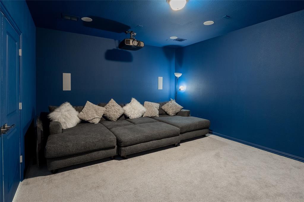 Dedicated room featuring recessed ceiling lighting, wall-mounted speakers, and a ceiling-mounted projector