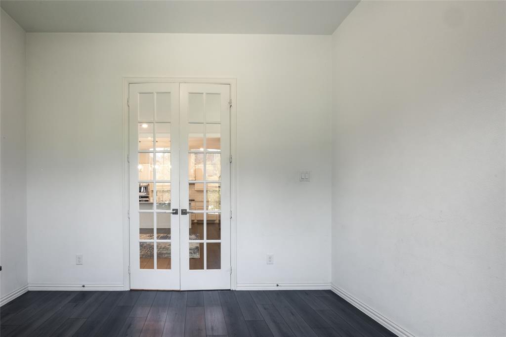 White French doors featuring glass panes and dark-toned hardware, set against dark wood-finish flooring