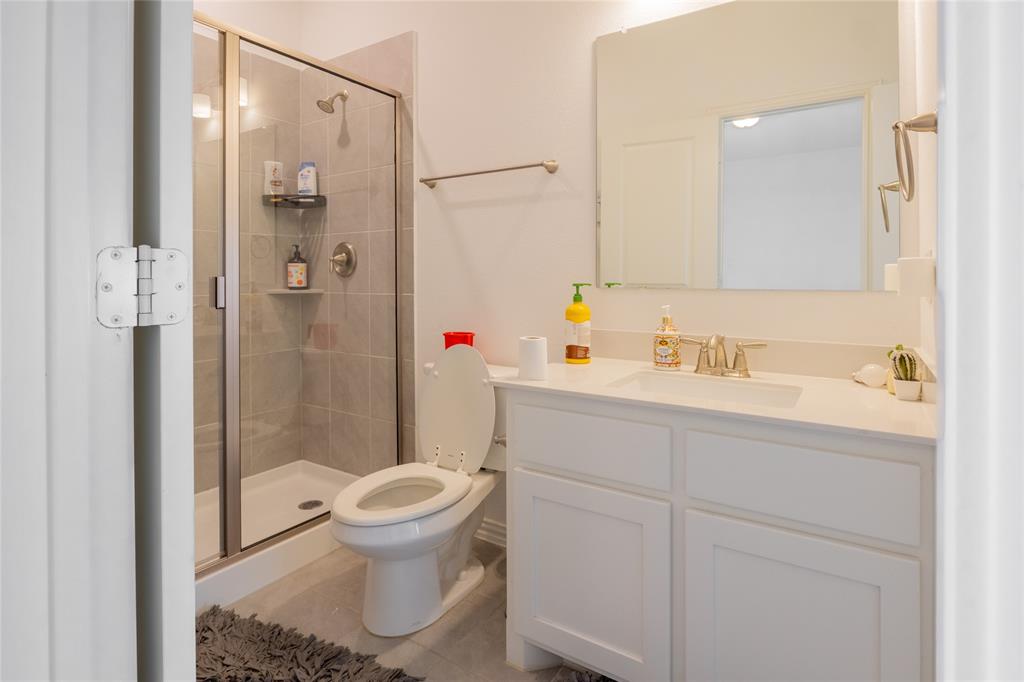 Bathroom featuring a white vanity with an integrated sink, polished metal faucet, walk-in shower with a glass enclosure, and a rectangular wall-mounted mirror