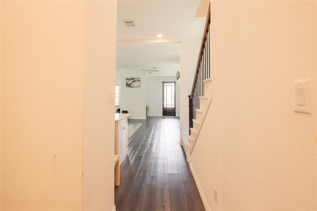 Interior space featuring dark wood-finish flooring, staircase with a dark wood handrail and vertical balusters, and a glass-paneled entry door
