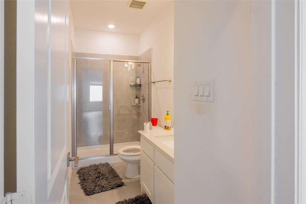 Bathroom featuring a glass-enclosed shower with tiled surround, white vanity cabinetry, integrated countertop sink, and recessed lighting