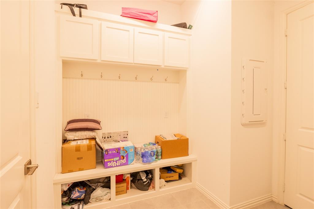 Built-in white storage cabinetry featuring overhead lockers, beadboard paneling with multiple metal coat hooks, and open lower cubbies