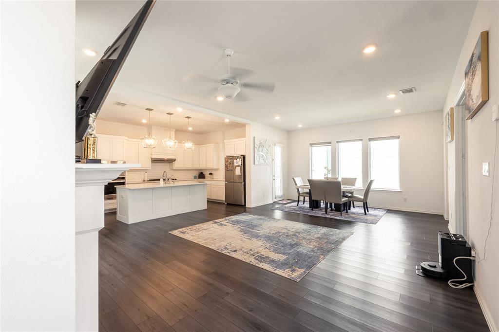 Open-concept interior featuring wood-finish flooring, recessed lighting, and a kitchen equipped with a central island and white cabinetry