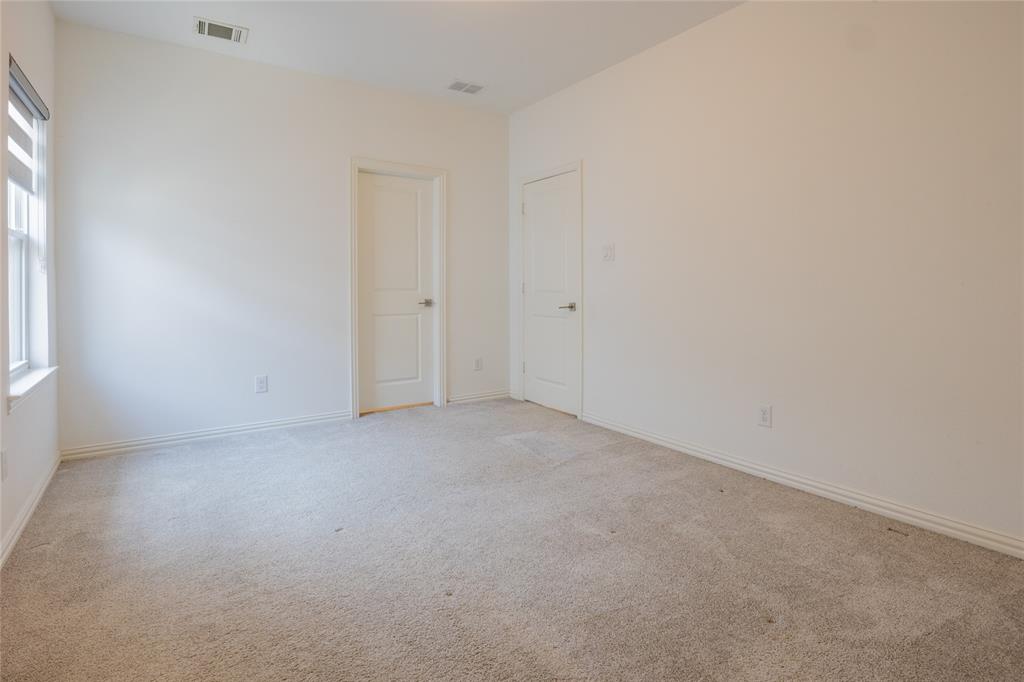 Neutral-toned wall-to-wall carpeting, two interior doors with brushed nickel hardware, and a single-hung window with a screen and horizontal window treatment