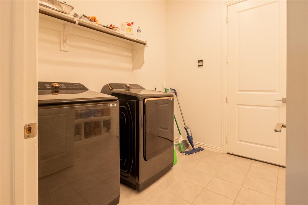 Utility room featuring neutral tile flooring, built-in shelving, and a solid-core interior door