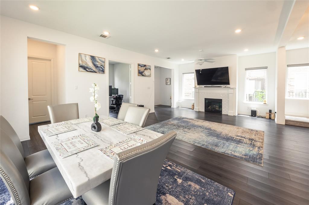 Open-concept living space featuring wood-finish flooring, recessed lighting, and a white brick fireplace with a decorative mantel