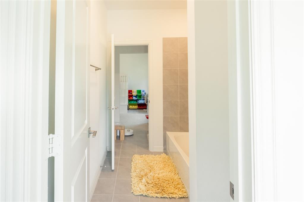 Bathroom featuring large-format neutral tile flooring and a built-in tub surround with matching tiled wall accents