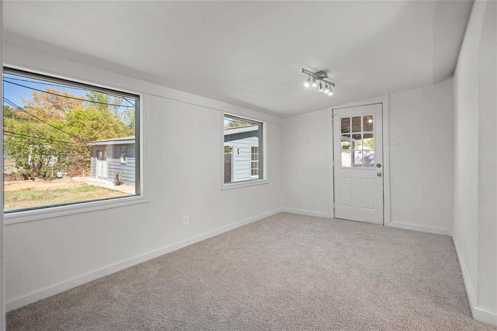 Interior room featuring neutral wall finishes, wall-to-wall carpeting, multiple windows, a multi-light track lighting fixture, and a glass-paneled exterior door