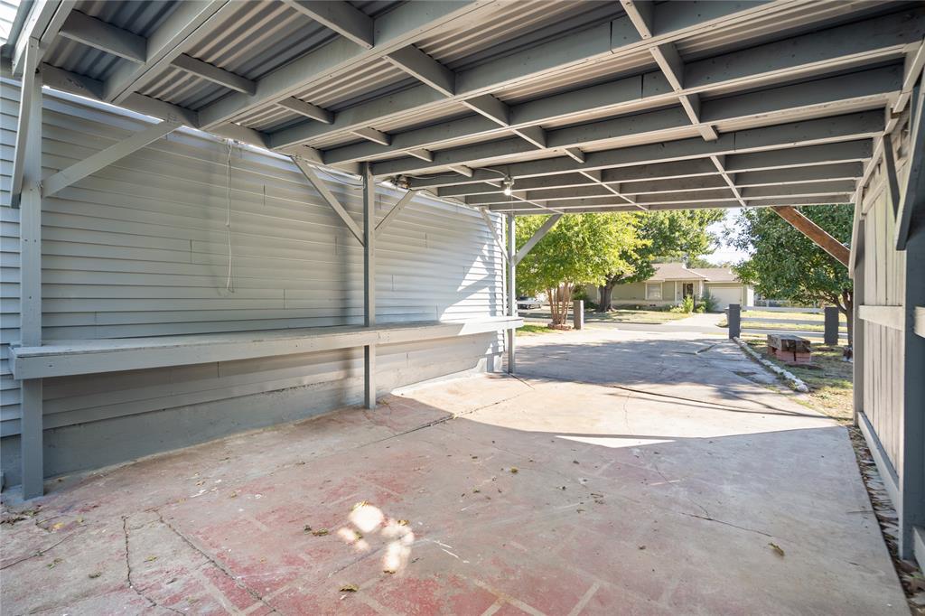 Covered carport featuring a structural beam frame, corrugated metal roof, horizontal siding wall, and built-in work surface