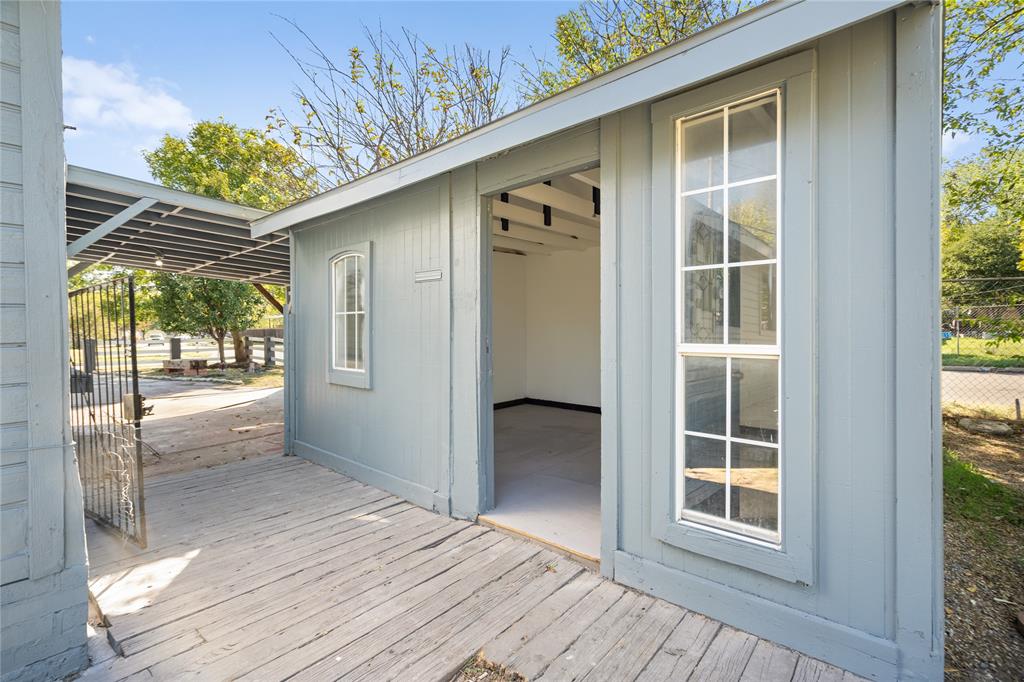 Outbuilding featuring wood-plank siding, an integrated covered porch, a tall multi-pane window, and an open entry