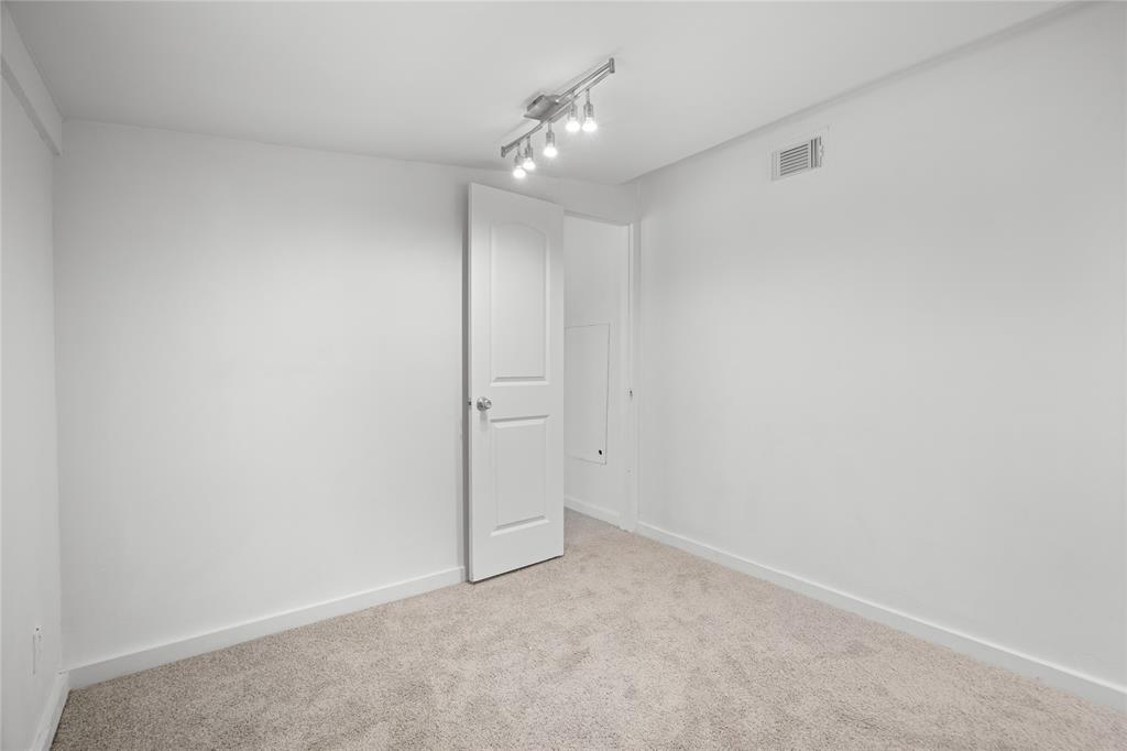 Room featuring neutral carpeting, a white paneled door, and a multi-directional track lighting fixture