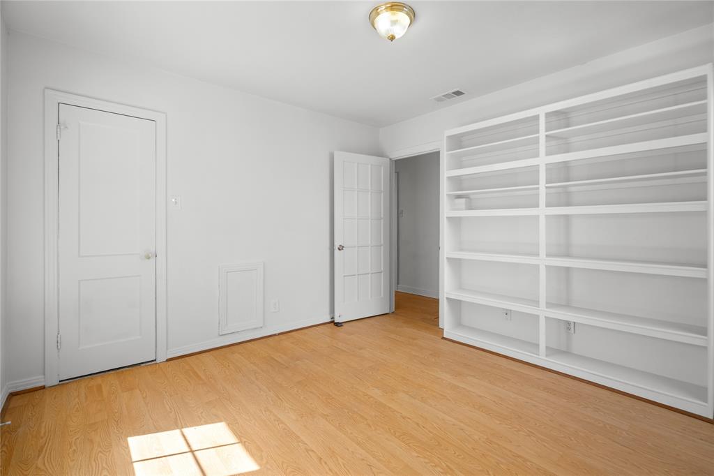 Built-in floor-to-ceiling shelving, wood-finish flooring, two-panel interior door, multi-lite glass door, and flush-mount ceiling light fixture