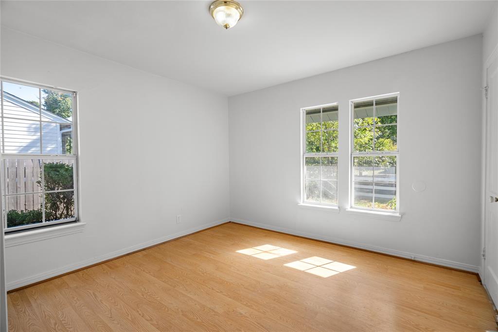 Interior space featuring wood-finish flooring, white walls, dual-pane windows with muntins, and a flush-mount ceiling light fixture